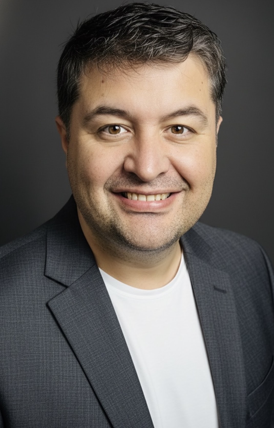 Prof. Dr. Ömer Faruk Rençber in a grey blazer, studio portrait.